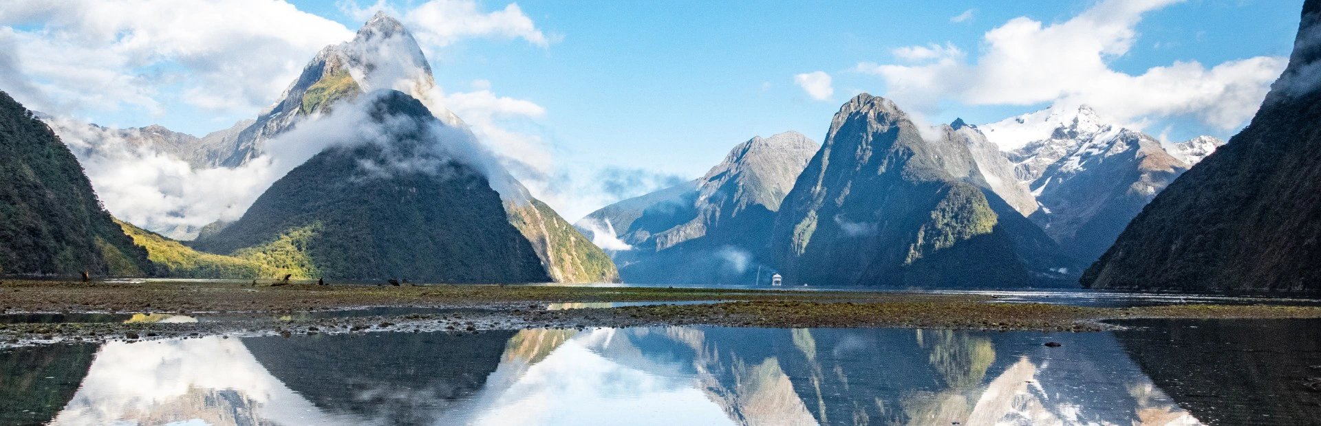 Berge spiegeln sich im glatten Wasser am Milford Sound in Neuseeland.