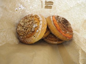 Verschiedene runde Gebäckstücke mit Nüssen, Zimtfüllung und Puderzucker in einer Papiertüte in Island