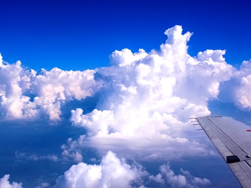 Flugzeugflügel in den weißen Wolken