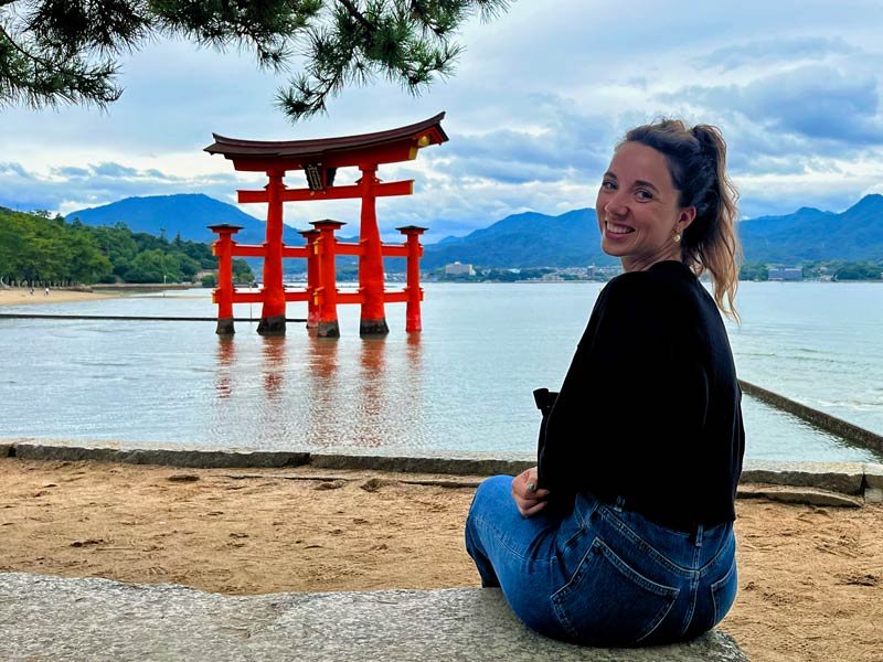 Reisende vor großem Torii im Wasser am Strand von Miyajima in Japan