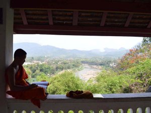 Mönch in einem Tempel mit Blick auf Luang Prabang in Laos