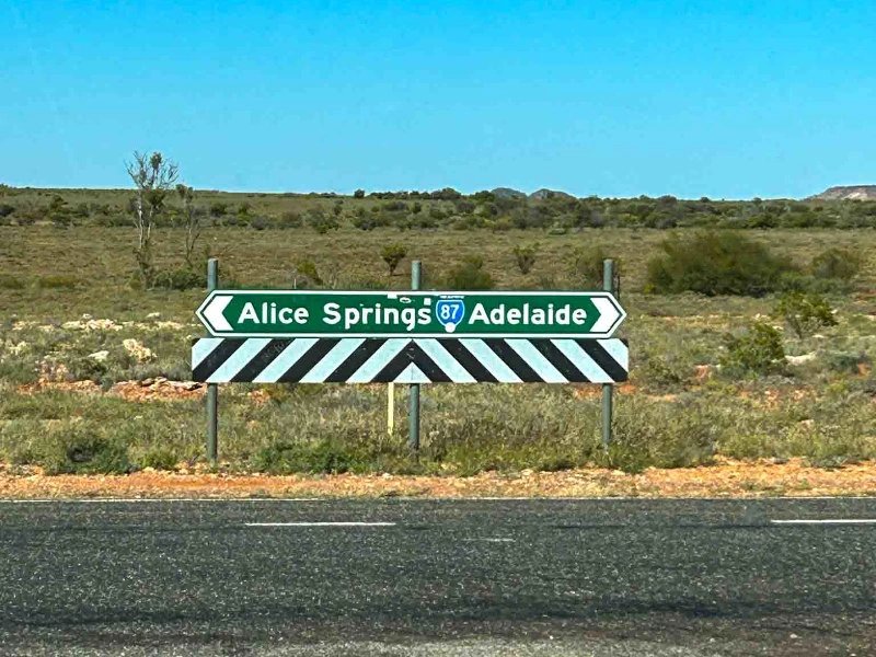 Schild zu Alice Springs und Adelaide im Outback von Australien