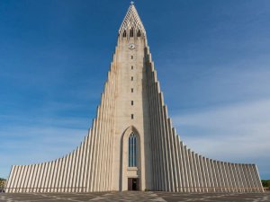 Hallgrímskirkja, hohe Betonkirche mit geometrischer Architektur und Turmspitze unter blauem Himmel in Reykjavík, Island