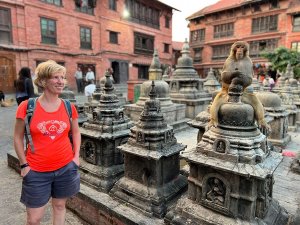Touristin vor einer Tempelanlage in Kathmandu auf der ein Affe sitzt, Nepal