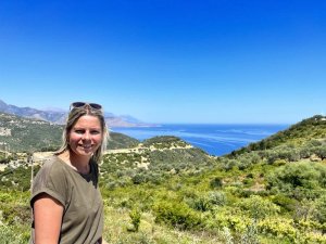 Frau lächelt mit Blick auf Albanische Küste grüne Olivenhügel und blaues Meer