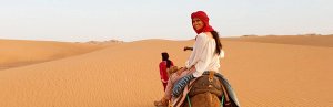 Frau reitet auf Kamel in Marokkos Wüste