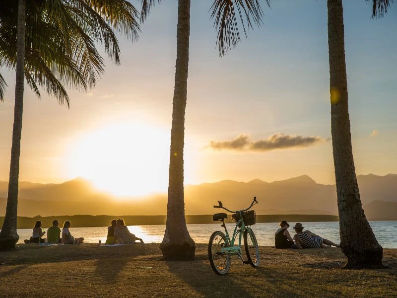 Eine Gruppe Menschen schaut in den Sonnenuntergang bei Port Douglas