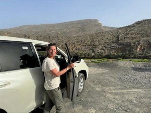 Reisende mit dem Mietwagen vor den Bergen in Jebel Akhdar
