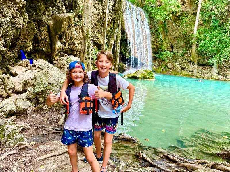 Kinder vor den Wasserfällen im Erawan Nationalpark in Thailand