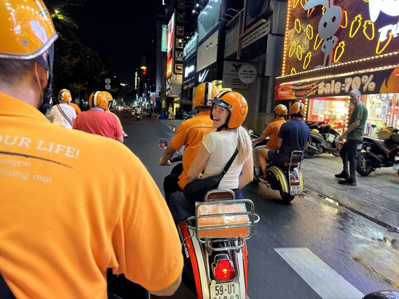 Reisende auf dem Rücksitz einer Vespa währen der Food Tour in Ho-Chi-Minh-Stadt, Vietnam