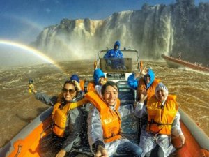 Reisende im Boot mit Rettungwesten vor den Iguazu Wasserfällen in Argentinien