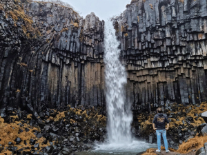 Blog Herbstreiseziele Island Wasserfall an schwarzen Klippen