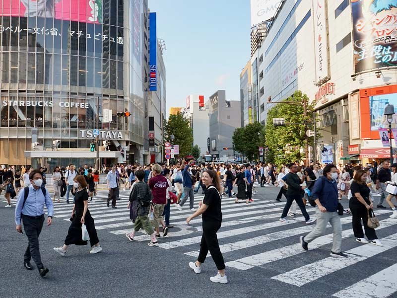 Reisende bei einer Ampelphase auf Shibuya Crossing in Tokio