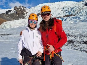 Zwei Menschen mit Helmen und Kletterausrüstung lächeln auf einem Gletscher in Island