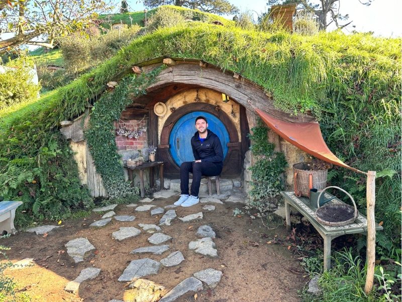 Mann sitzt in Hobbiton vor einer Tür