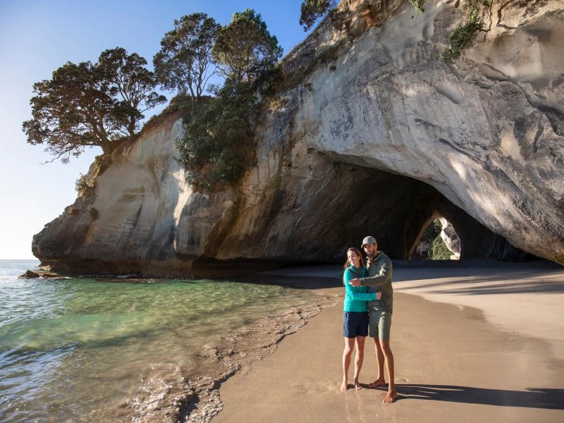 Paar posiert vor der Cathedral Cove in Coromandel, Neuseeland.