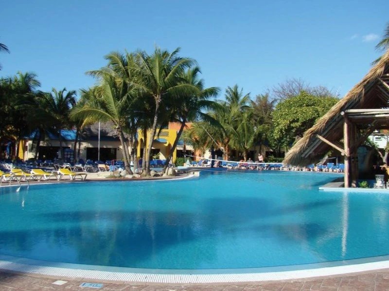 Großer Resortpool mit Palmen, Liegestühlen, Gebäuden und Swim-up-Bar mit Strohdach in Varadero, Kuba