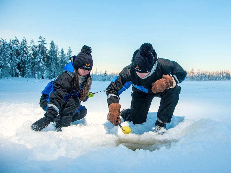 Reisende beim Eisfischen in Lappland