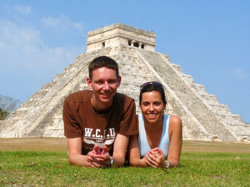 Lächelnder Mann und lächelnde Frau im Gras vor der Pyramide von Chichén Itzá in Yucatán, Mexiko