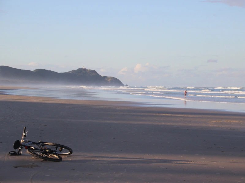 Fahrrad liegt an einem weiten Sandstrand in Byron Bay in Australien