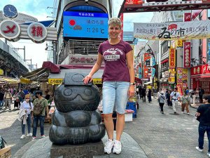 Reisende auf einer Statue vor einer großen und bunten Einkaufsstraße in Tokio in Japan
