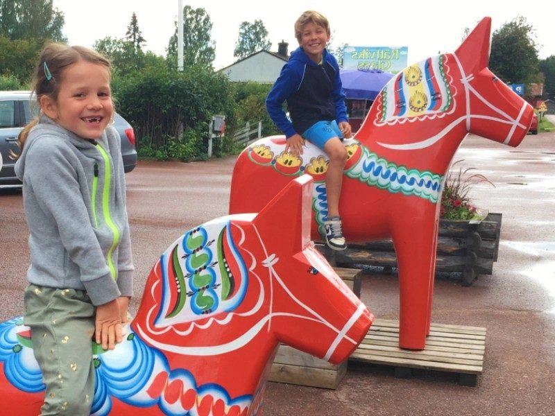 Kinder auf roten Dalapferd-Figuren in Dalarna, Schweden