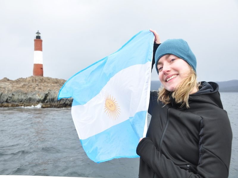 Frau mit Flagge am Ushuaia Beagle Kanal
