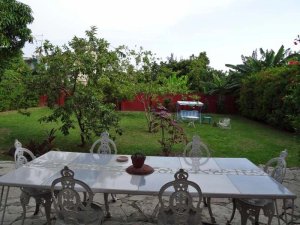 Außenbereich eines Restaurants mit Blick auf einen üppigen Garten mit Bäumen, roter Mauer und Schaukel in Baracoa, Kuba