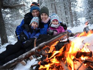 Familienfoto am Feuer im Schnee in Lappland