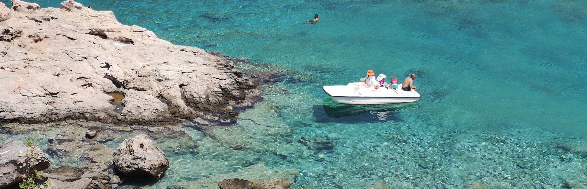Weißes Boot mit Familie im klaren Wasser an der Küste