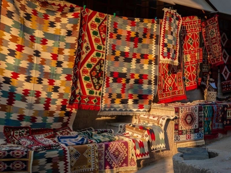 Bunte Teppiche und Textilien im Sonnenlicht auf Markt in Gjirokastra, Albanien