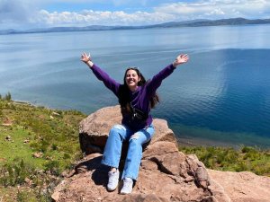 glückliche Frau am Titicacasee in Peru, die die atemberaubende Aussicht auf das Wasser und die umliegenden Berge genießt