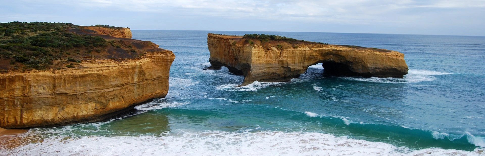 London Arch in Australien mit natürlichem Felsbogen neben Klippen, türkisfarbenem Meer und Wellen am Sandstrand