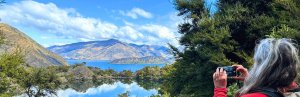 Frau mit Kamera vor See in Neuseeland