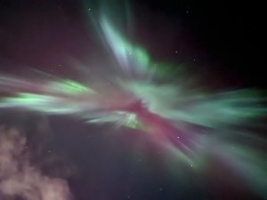 Grünes und violettes Nordlicht leuchtet am dunklen Sternenhimmel in Island