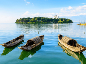 Drei Boote vor einer Bucht am Erhai See in Dali bei den Baidörfern mit einer Insel im Hintergrund