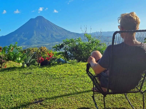 Mann schaut vom Liegestuhl auf den Arenal Vulkan in Costa Rica