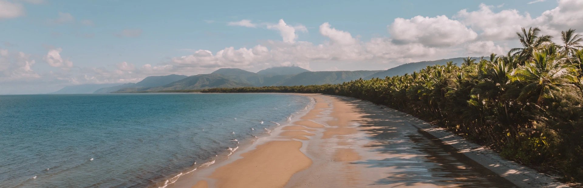 Langer Sandstrand mit Palmen in Port Douglas in Australien