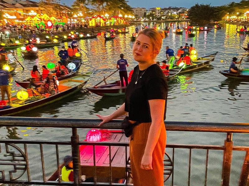 Reisende auf Brücke vor bunt beleuchteten Booten in Hoi An, Vietnam