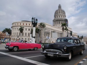 Rosa Cabrio und schwarze Limousine auf einer Straße in Havanna mit dem El Capitolio im Hintergrund in Kuba