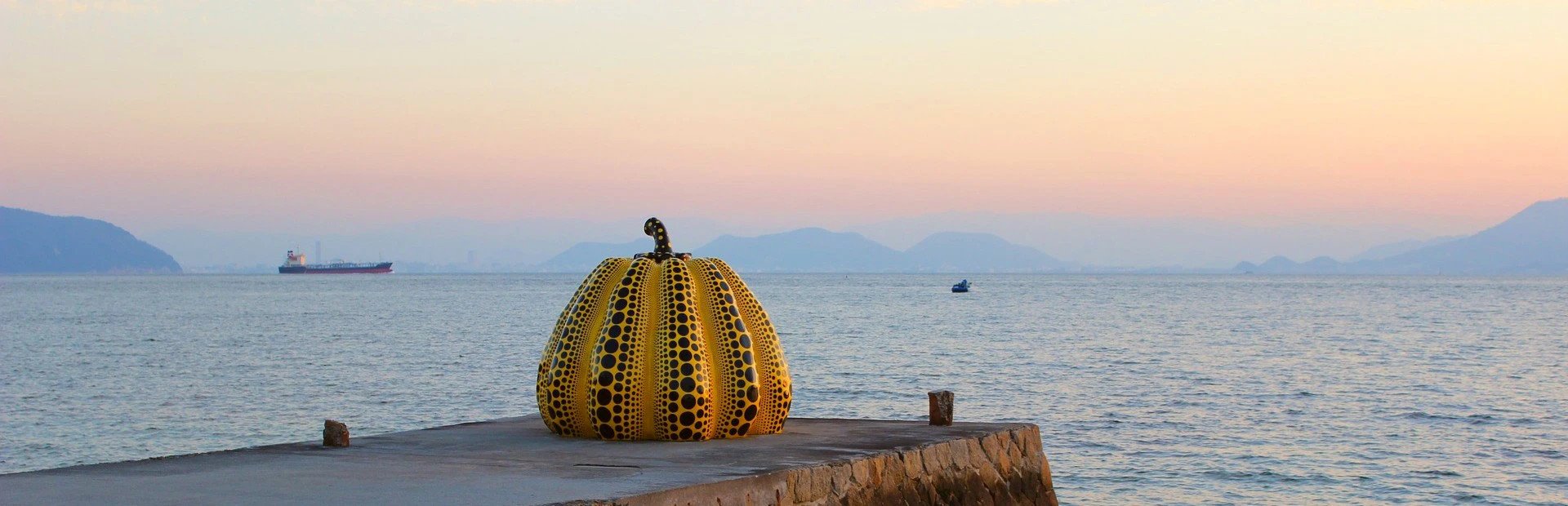 Kürbis von Yayoi Kusama auf einem Steg vor dem Meer bei Abenddämmerung auf Naoshima