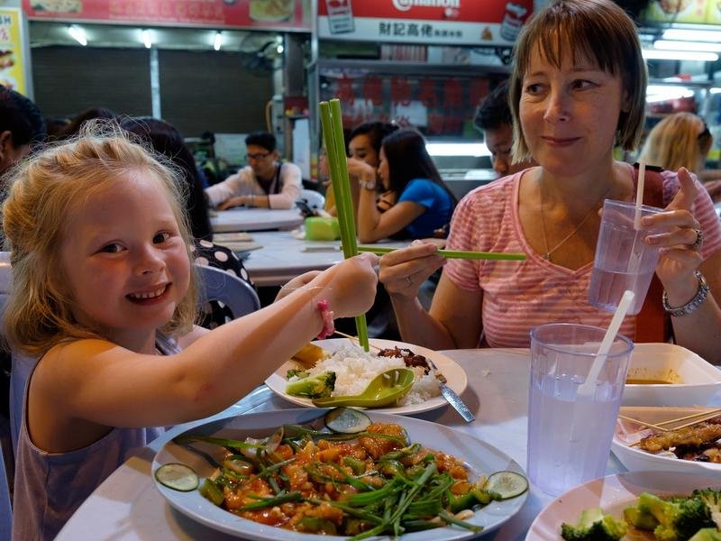 Tochter und Mutter essen mit Stäbchen
