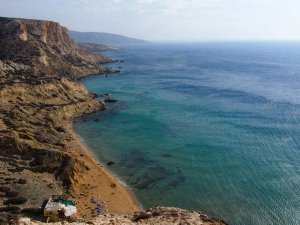 Blick von oben auf Klippen, einen roten Strand und das Meer
