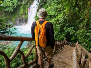 Reisender geht Treppenstufen zu Wasserfall hinunter