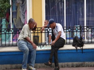 Zwei Männer spielen Schach auf einer Bank im Freien, während ein dritter Mann zuschaut in Havanna, Kuba