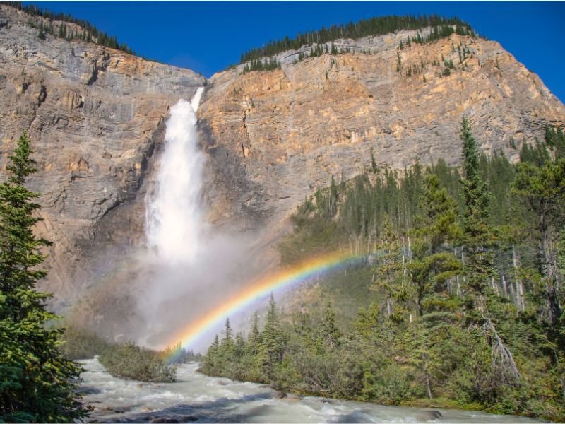 Ein Wasserfall, der von den Felsen herabstürzt, mit einem Regenbogen davor