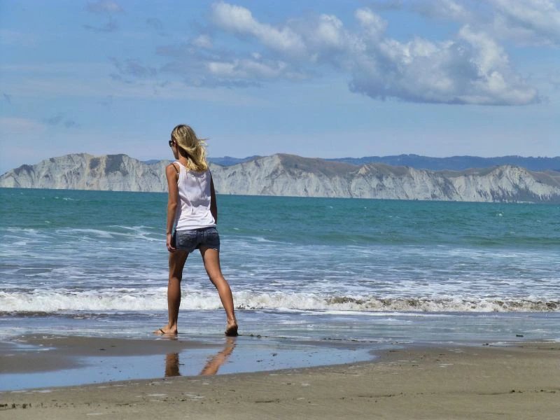 Frau läuft über den Strand am East Cape in Neuseeland.