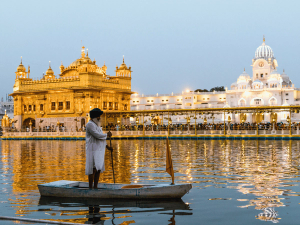 Einheimischer auf einem Ruderboot vor dem goldenen Tempel in Amritsar, Indien