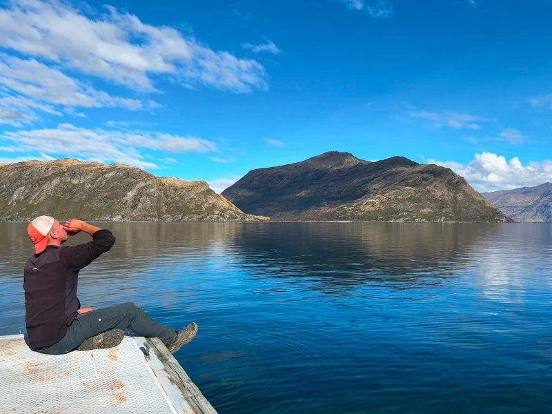 Ein Mann trinkt Wasser aus einem See in Wanaka