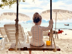 Mädchen auf Schaukel am Meer